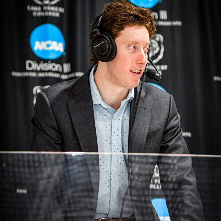 A man wearing headphones and a suit speaking into a microphone.